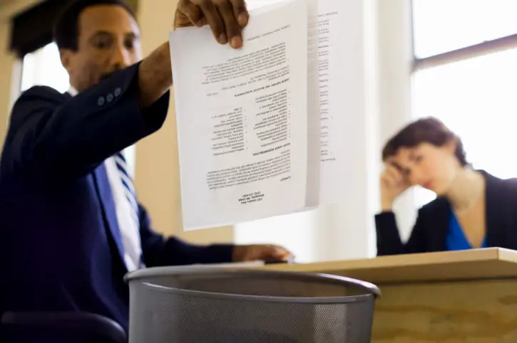 Businessman throwing away report into trash